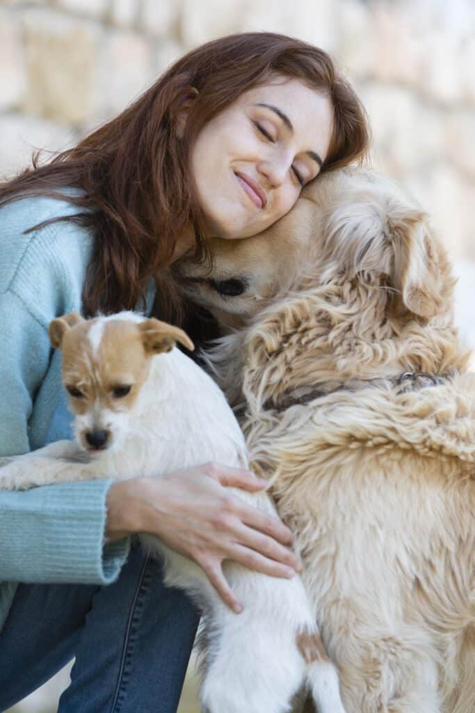 Femme qui fait un câlin à ses deux chiens